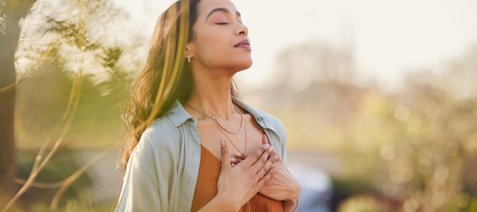 Woman practicing mindfulness in a park, finding inner peace through deep breathing.